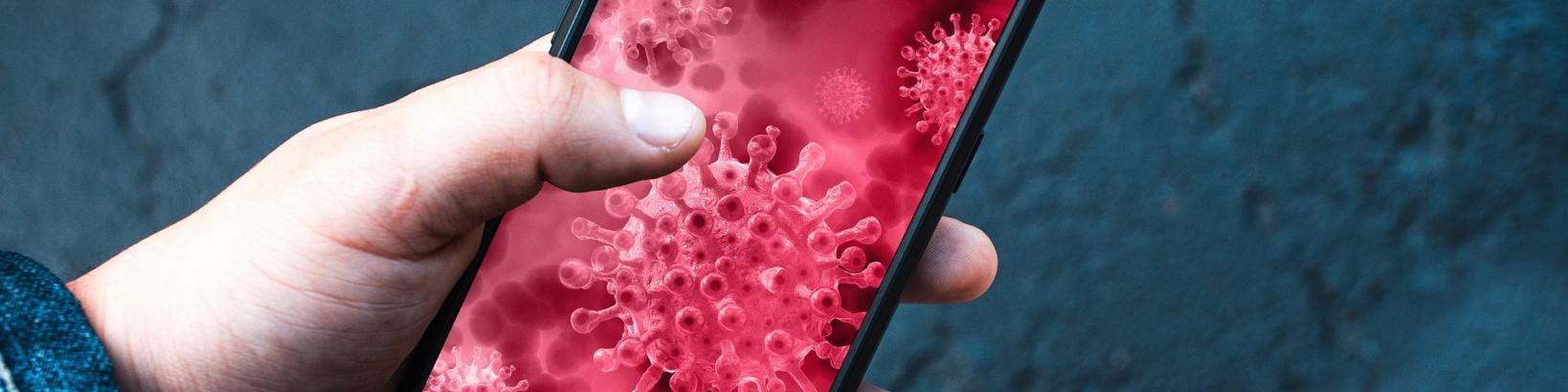 a hand holding a smartphone displaying an image of a virus