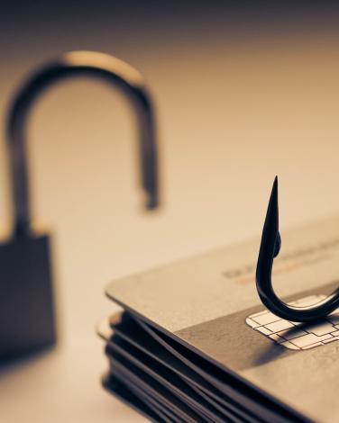 a hook on a pile of credit cards with an open lock in the background